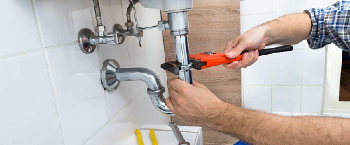 Close-up Of Male Plumber Fixing Sink In Bathroom